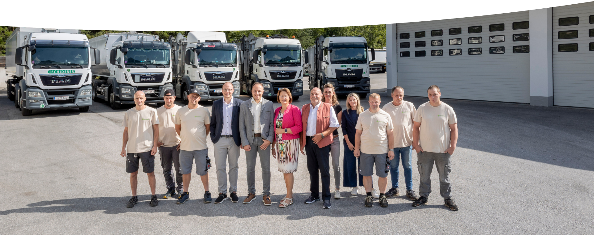 Eine Gruppe von Menschen steht vor den Lastwagen von Entsorgung Tiere, die vor einem Garagengebäude geparkt sind.